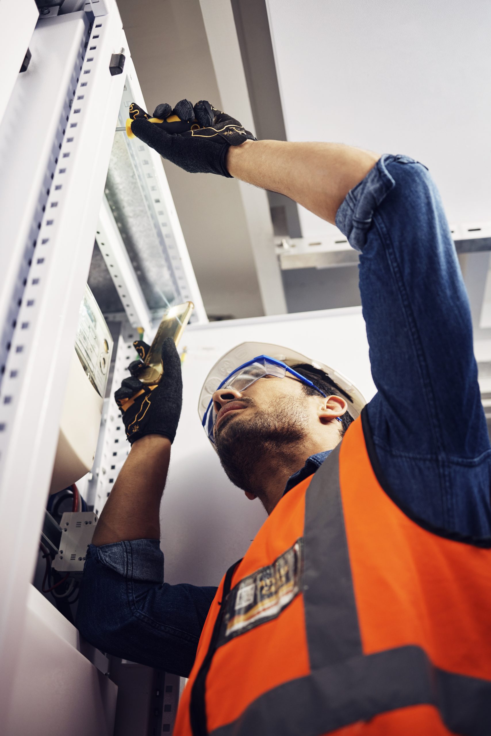 Engineer, electrician and maintenance man with screwdriver in control room for power box. Male technician person for inspection service for engineering, electricity or energy supply repair with torch.
